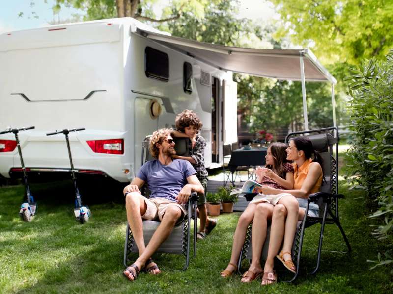 Familie nyder den friske luft foran deres autocamper på campingpladsen