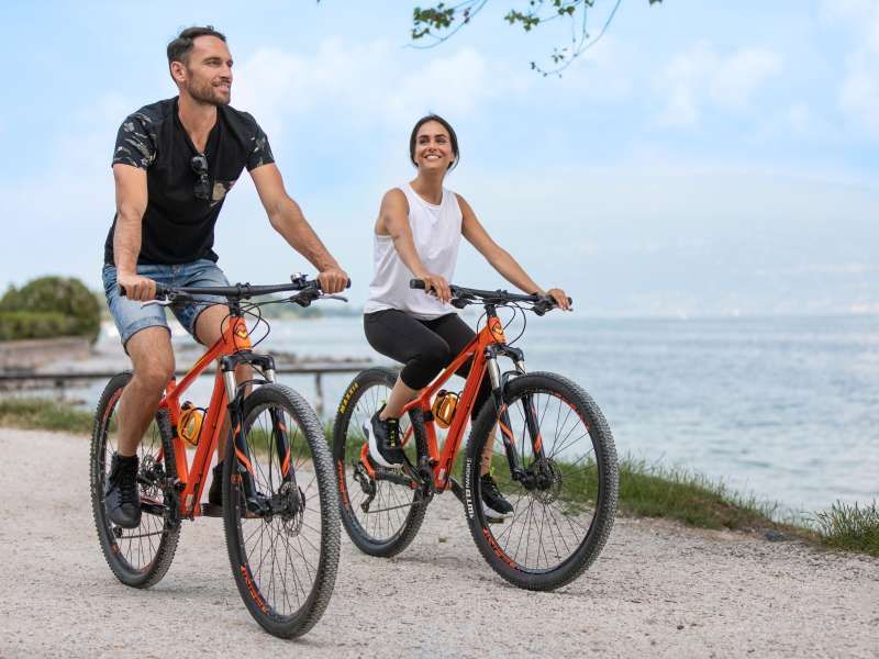 Coppia che pedala sul lago di Garda con bici prese a noleggio