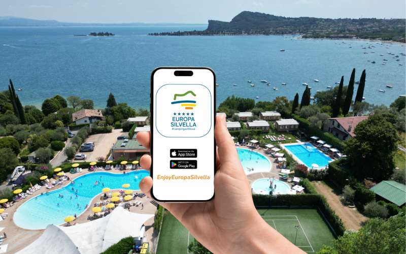 Main tenant un smartphone affichant l'icône de l'application Enjoy Europa Silvella