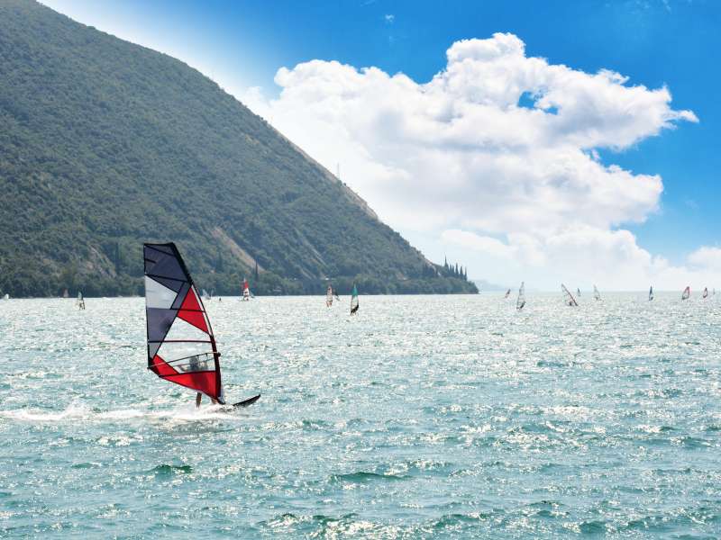 Een persoon die windsurft op het Gardameer