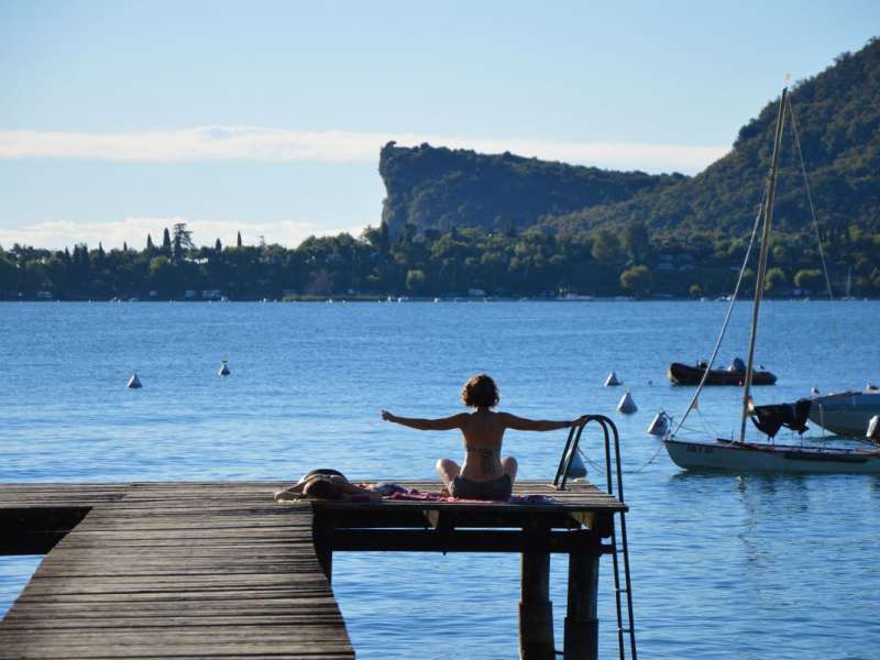 Femme pratiquant le yoga sur le ponton d'Europa Silvella, au bord du lac de Garde